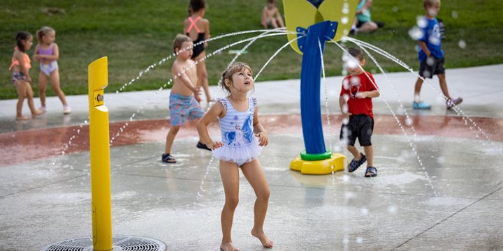 Children playing on a splash pad with an acrylic flower-shaped spray element 