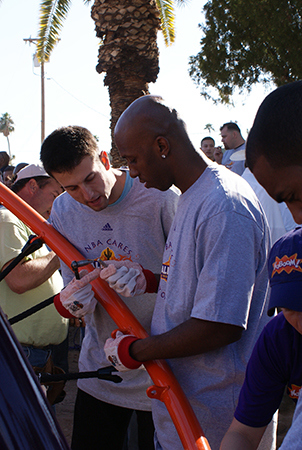 Two men help install a net structure. 