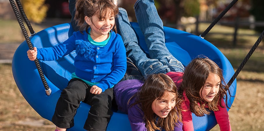 Three girls swinging on a freestanding Oodle Swing.